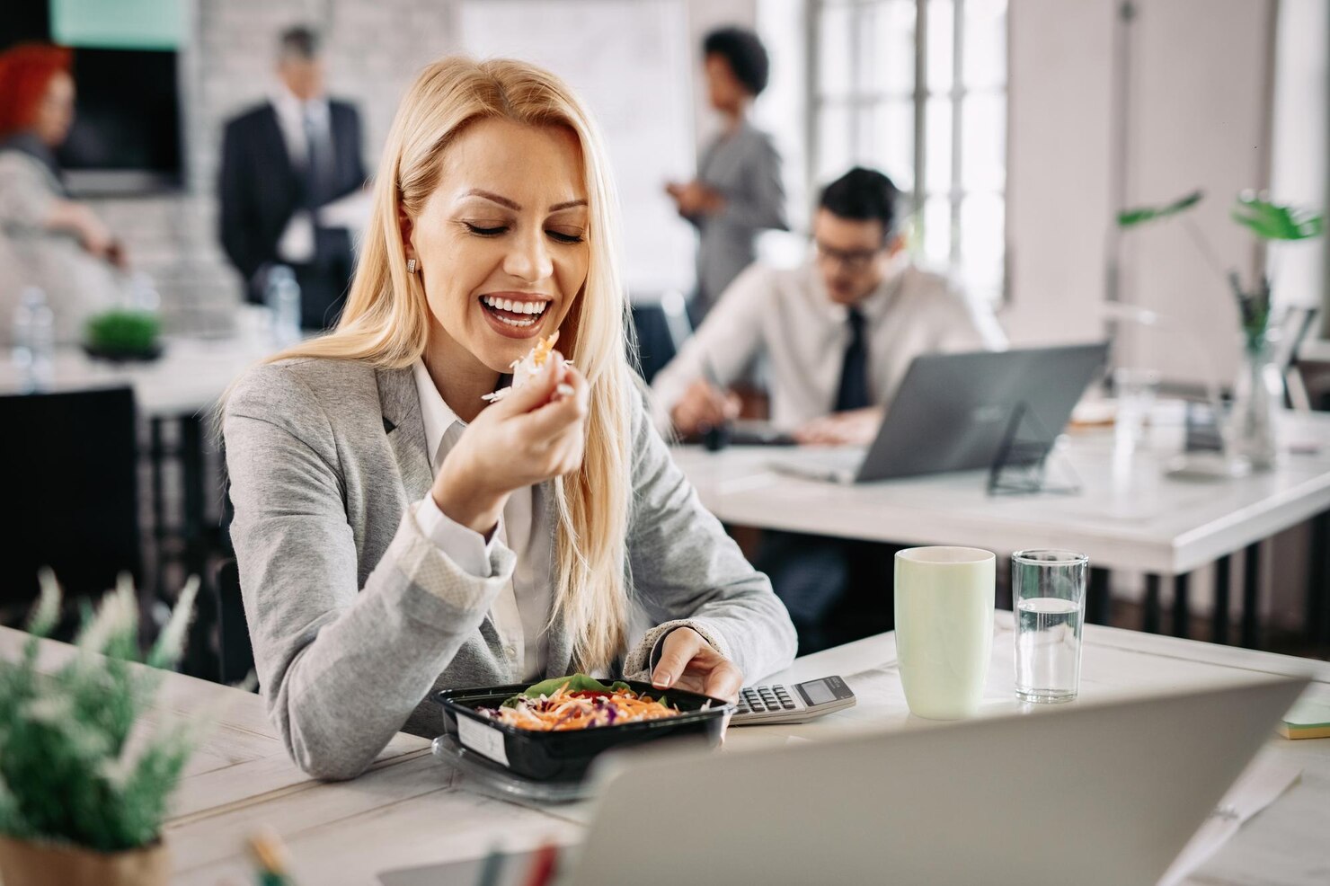 Mulher a comer uma comida caseira no escritório, depois de receber refeições para empresas